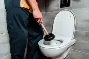 Mann mit Pömpel am WC: Wird ein Notdienst Toilette verstopft benötigt?